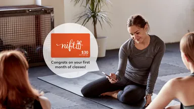 female yoga teacher smiling at her phone in class 