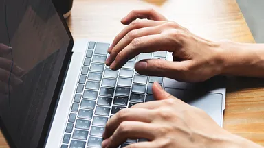 Hands typing on a Macbook