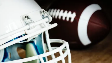 Football helmet and football in background on hardwood floor