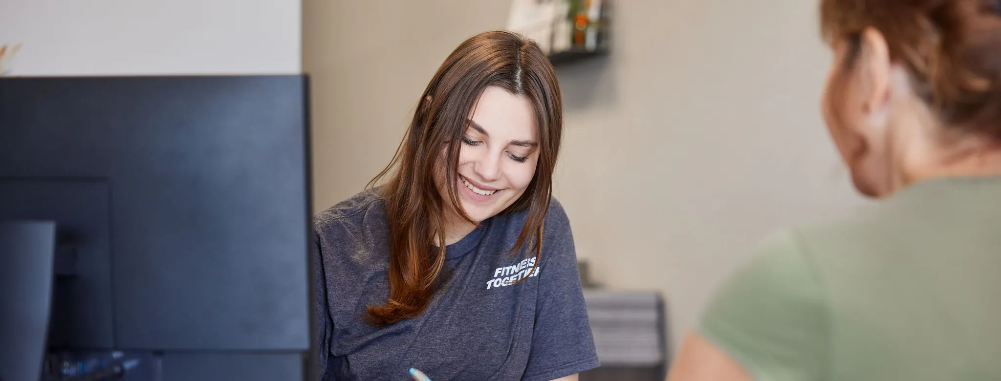 woman at desk writing in front of client