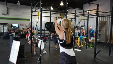 Woman exercising with heavy weights  in a high-intensity fitness studio