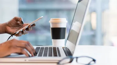 woman on laptop and smartphone with coffee cup and glasses