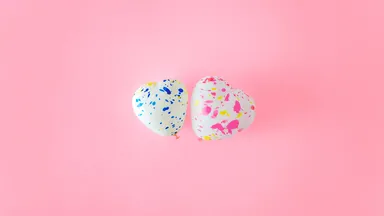 two balloon hearts on pink background