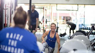 woman smiling and man working out in gym
